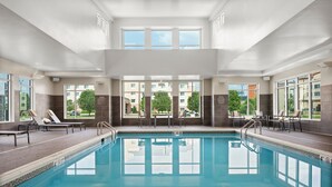 Une piscine intérieure offrant une vue dégagée sur l’extérieur grâce à de grandes fenêtres.