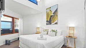 Ein modernes Hotelzimmer mit einem großen Bett, Blick auf die Stadt und einem großen Fenster.