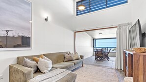 Ein geräumiger Wohnbereich mit einer Couch, einem Esstisch und Blick ins Freie.