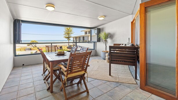 Ein Balkon mit Esstisch und Stühlen, einer Topfpflanze und Meerblick.