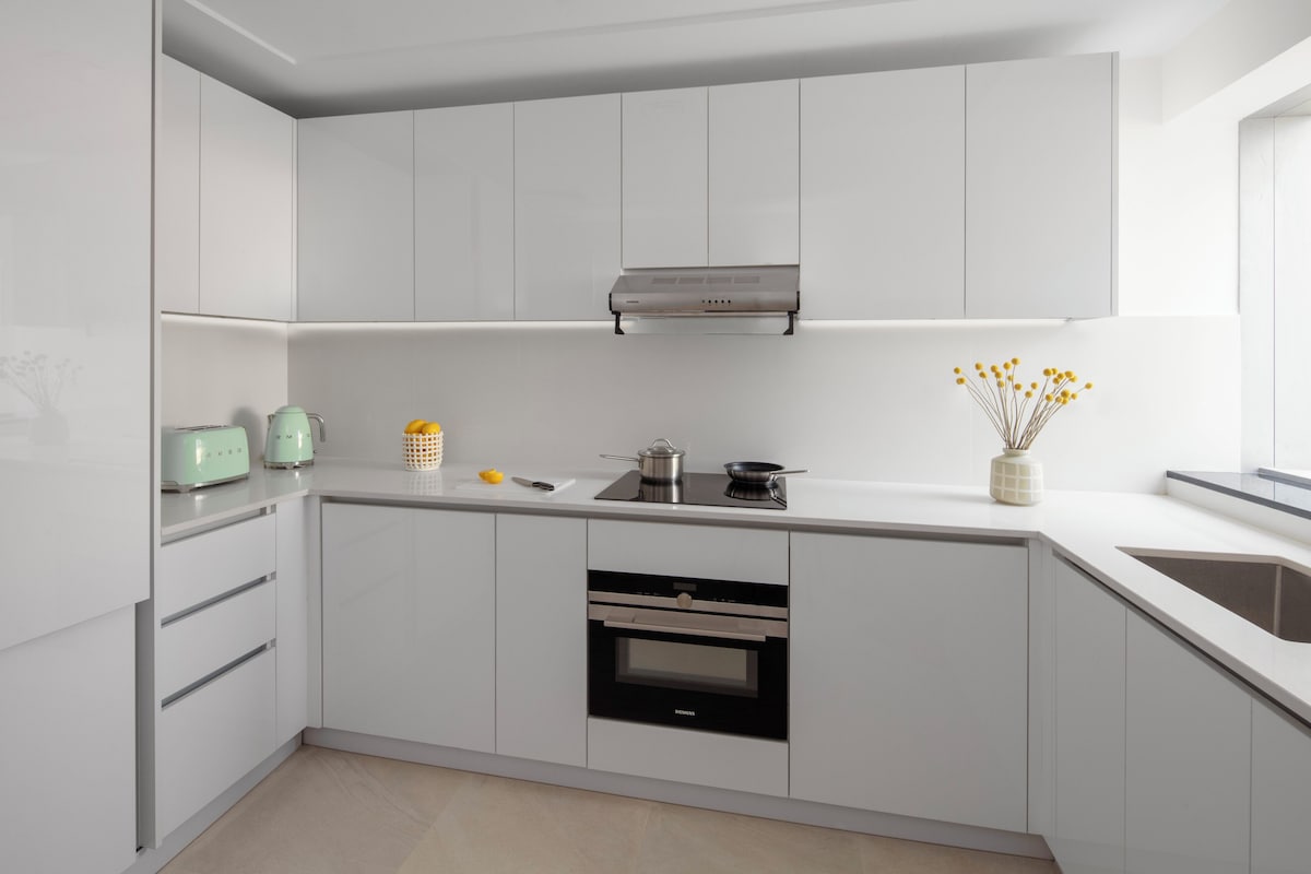 A modern kitchen with white cabinetry, a built-in oven, and a Siemens range hood.