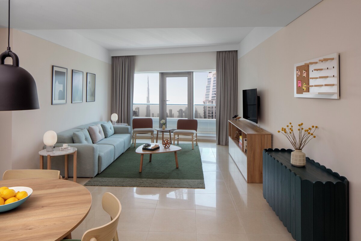 A modern living room with a sofa, coffee table, and a dining area with a bowl of lemons.