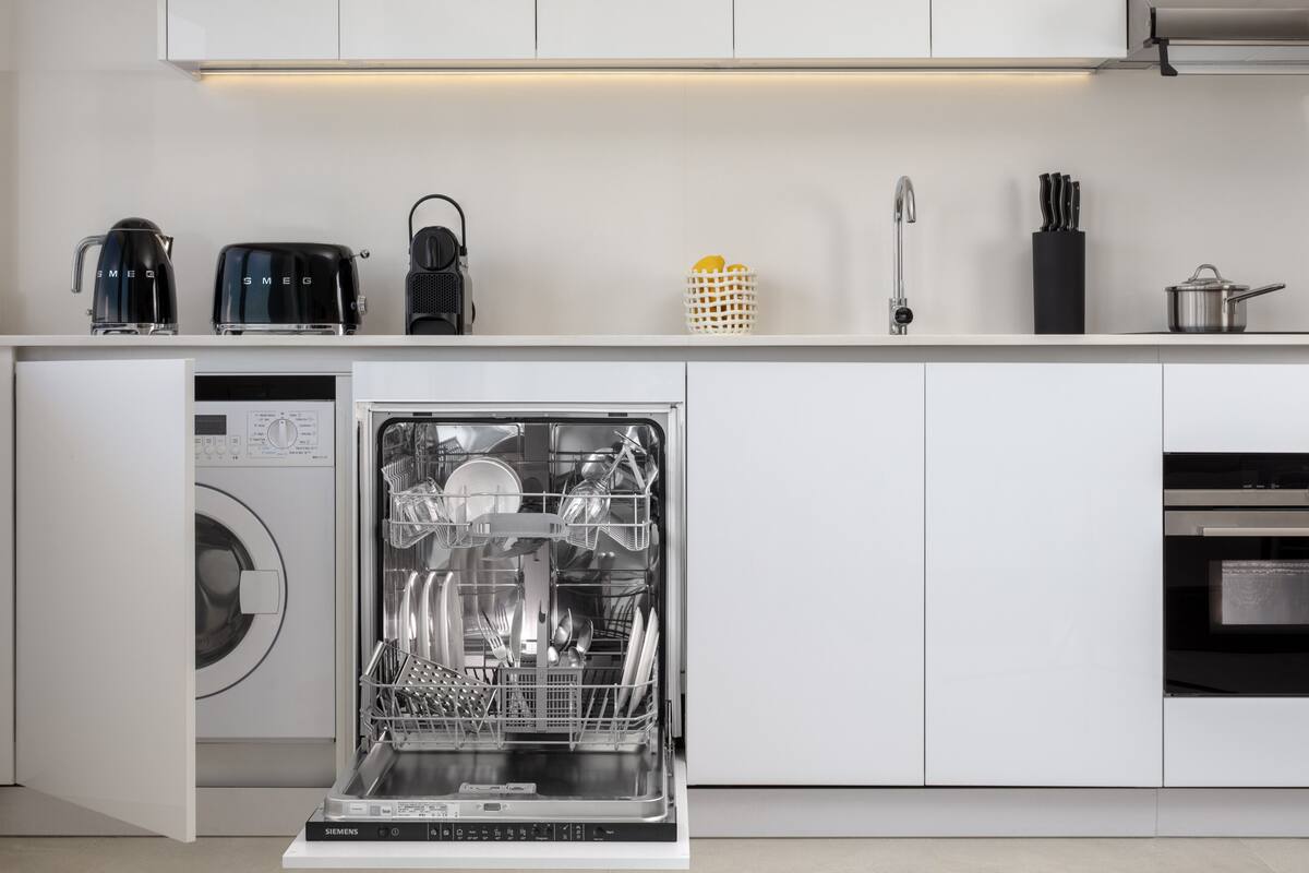 Une cuisine moderne équipée d’un lave-vaisselle, d’une machine à café et d’une bouilloire.