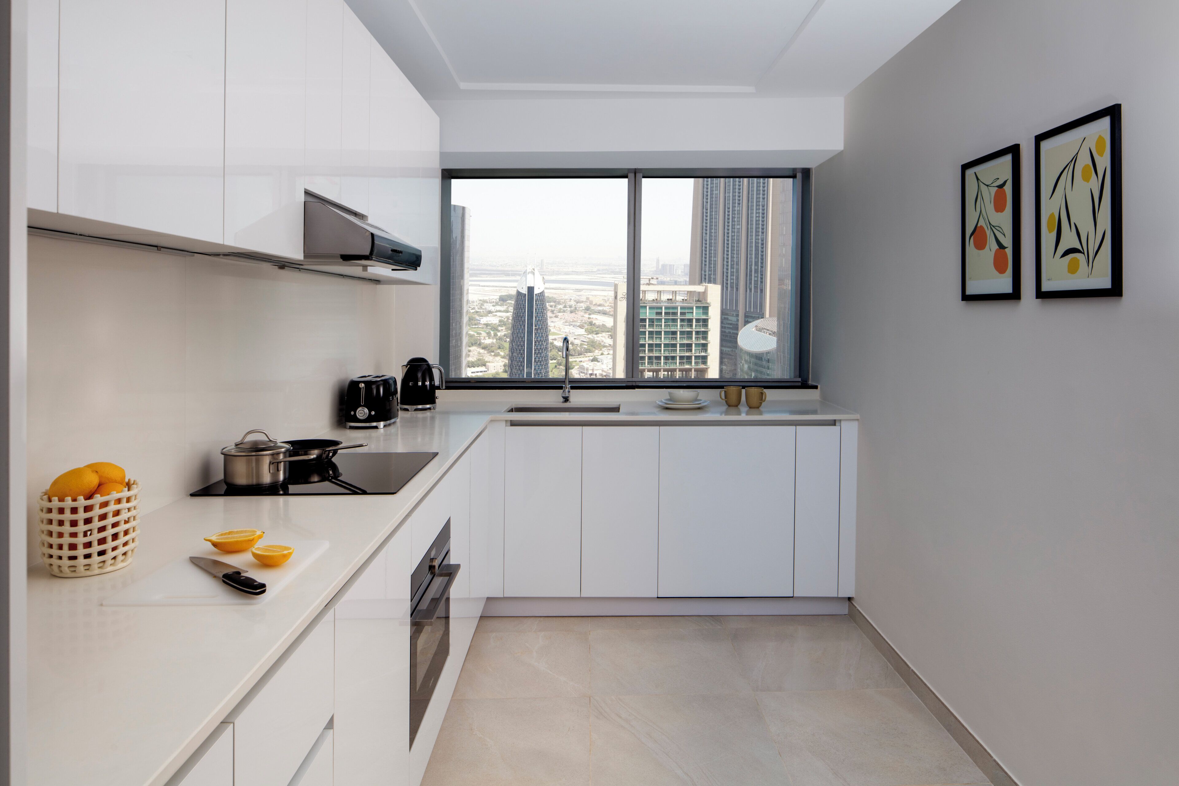 A modern kitchen with white cabinetry, a large window with a city view, and a sink.
