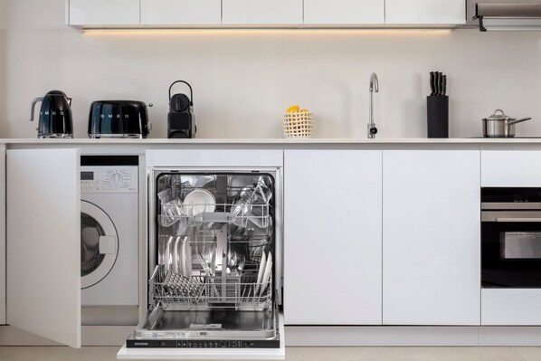Une cuisine moderne équipée d’un lave-vaisselle, d’une machine à café et d’une bouilloire.