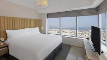 Een moderne hotelkamer met een groot bed, een televisie en een stadsgezicht door grote ramen.