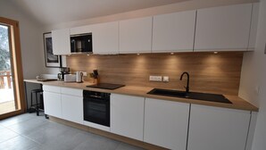 Een moderne keuken met witte kasten, een houten aanrecht, een ingebouwde magnetron, een spoelbak en een vaatwasser.