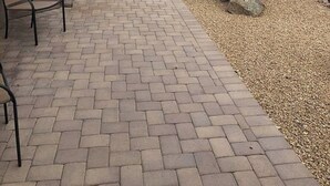 Un patio con piso de ladrillo, mobiliario exterior y un cactus grande.