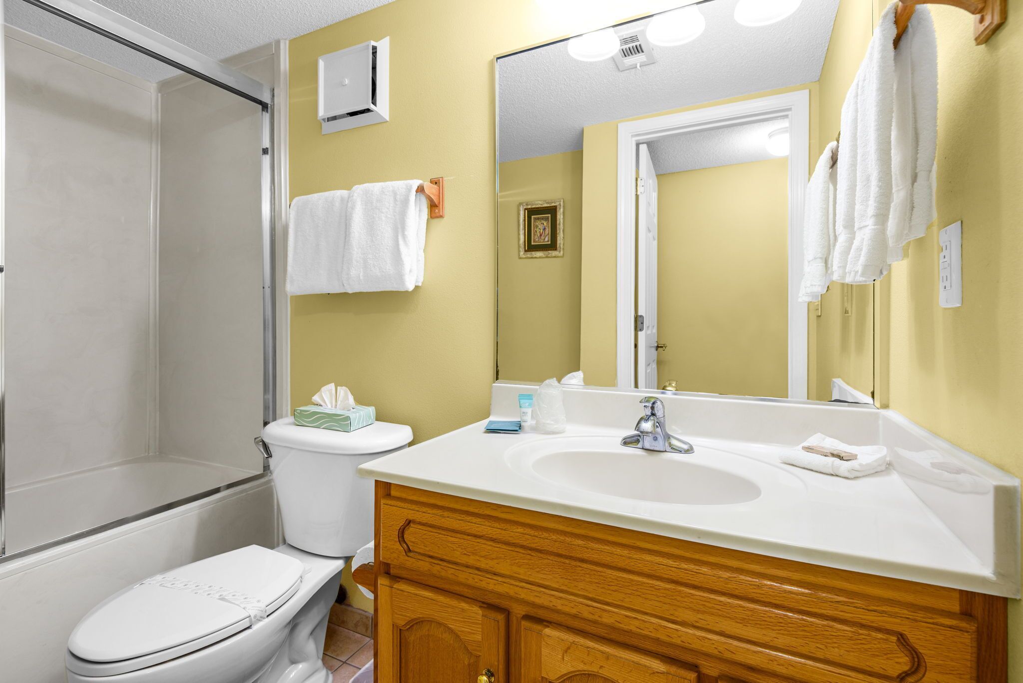 Un baño con ducha, inodoro, lavamanos y espejo.