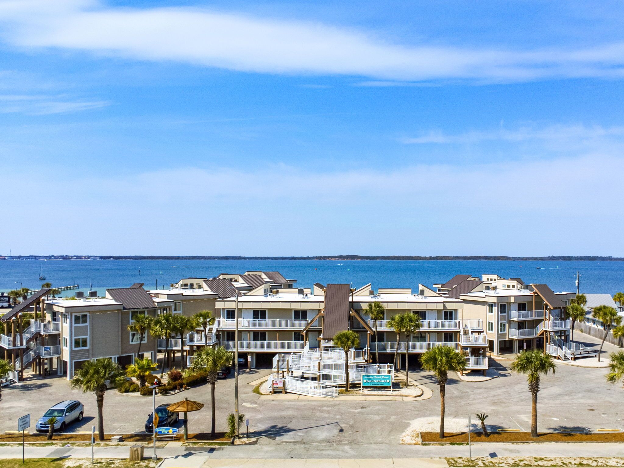 Un hôtel situé en bord de mer, composé de plusieurs bâtiments, doté d’un parking et agrémenté de palmiers.