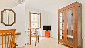Een kamer met een eettafel, stoelen, een kast, een televisie en een grote houten kast.
