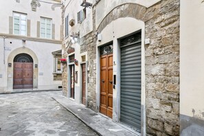 Eine enge Gasse mit Steinbauten, Holztüren und einem heruntergelassenen Metallverschluß.