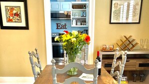 Une table à manger avec des chaises, un vase de fleurs et, au fond, une cuisine.