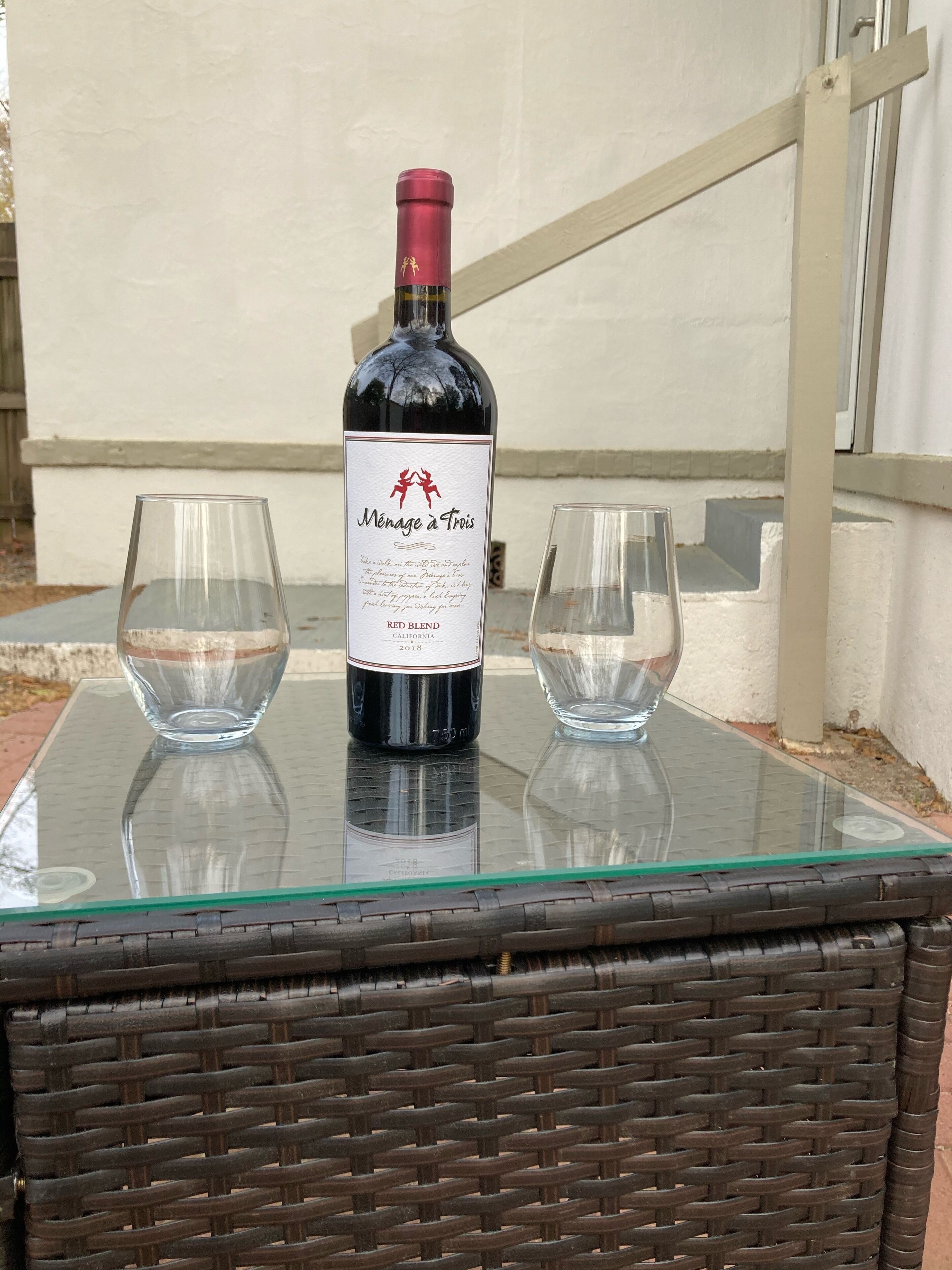 Uma garrafa de vinho e duas taças sobre uma mesa de vidro.