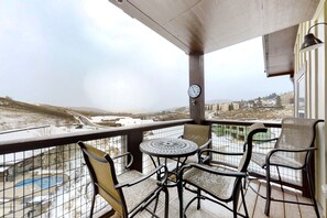 Enjoy the serene view from this balcony with a table for four and a clock on the wall.