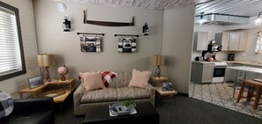 Ein Wohnzimmer mit Sofa, Couchtisch und einer Küchenzeile mit Schränken und Herd.