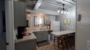 Uma cozinha compacta com fogão embutido, pia e banquetas.