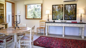 A dining area with a round table, chairs, a red patterned rug, a white cabinet, and two wall-mounted lamps. - Seaside Retreat - Premium Luxe Accommodation: 3rd night complimentary: winter 26 (Port Elliot)