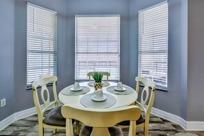 Cozy dining area with a round table for four, surrounded by comfortable chairs and a small potted plant.