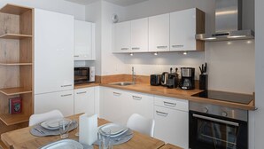 Una cucina moderna con mobili bianchi, un piano di lavoro in legno, un forno a microonde, un tostapane, una macchina da caffè e un forno.