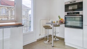 Een moderne keuken met witte kasten, een inbouwoven en een raam met uitzicht op een stadsbeeld.