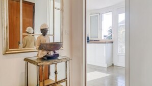 Een kamer met een houten consoletafel, een spiegel en een beeld van een figuur met een kom.