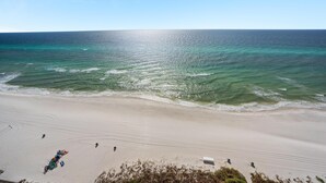 A beach with clear turquoise waters, a sandy shore, and a few people and beach equipment. - Triple en-suite unit with miles-long views of the Gulf | Beach Chairs Included (Panama City Beach)
