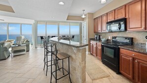 A modern kitchen with a large island, built-in appliances, and a view to the ocean. - Triple en-suite unit with miles-long views of the Gulf | Beach Chairs Included (Panama City Beach)