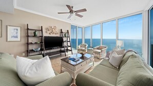A spacious living room with a large flat-screen TV, comfortable seating, and a view of the ocean. - Triple en-suite unit with miles-long views of the Gulf | Beach Chairs Included (Panama City Beach)