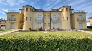A multi-story residential building with a symmetrical facade, balconies, and a well-maintained lawn.