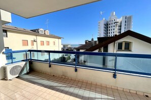 A balcony with a glass railing overlooking a cityscape.