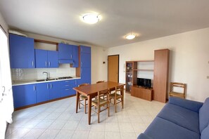 Une cuisine de taille réduite avec des meubles de couleur bleue, une table à manger en bois et un canapé bleu.