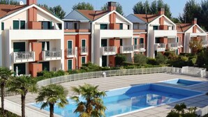 Un hôtel moderne composé de plusieurs bâtiments à deux étages, doté d’une piscine centrale et d’un espace extérieur clos agrémenté de palmiers.