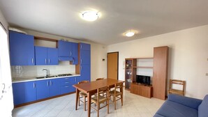 Une cuisine de taille réduite avec des meubles de couleur bleue, une table à manger en bois et un canapé bleu.