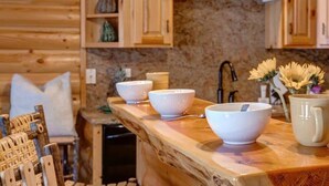 A wooden kitchen with white bowls, a mug, and a sink.
