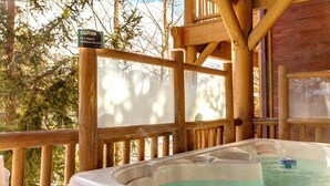 A hot tub with a caution sign, wooden deck, and surrounding trees.