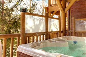 A hot tub with a caution sign, wooden deck, and surrounding trees.