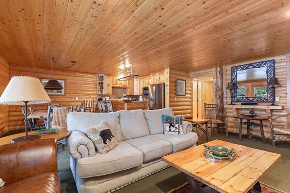 L’intérieur d’une cabane en rondins, avec un canapé, une table à manger et un coin cuisine.