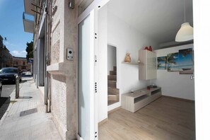 A modern apartment with a staircase, a wooden floor, and a view of the street.