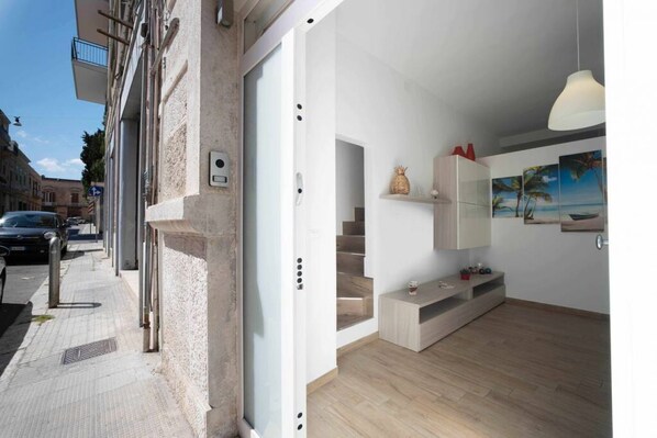 Un apartamento moderno con escalera, piso de madera y vista a la calle.