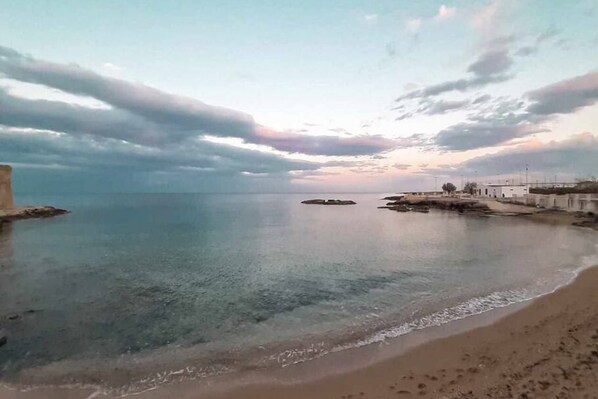 A coastal scene with a clear sky, calm sea, and a sandy beach.