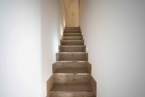 A wooden staircase with a handrail, leading upwards in a narrow space.