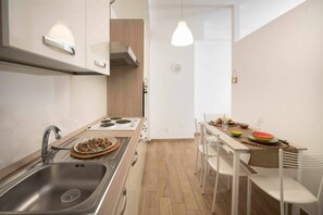 Una cocina moderna con un lavamanos de acero inoxidable, una estufa y una zona de comedor con una mesa preparada para dos.