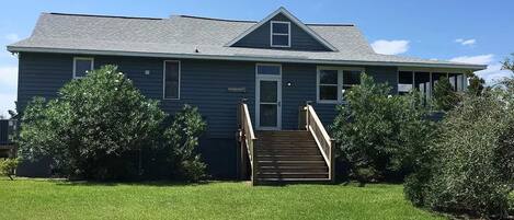A two-story house with a front porch and a staircase leading to the door.