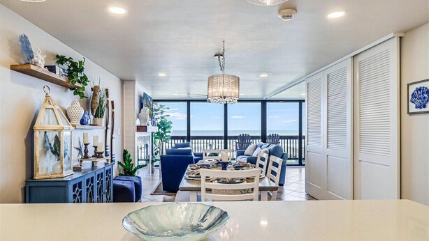A spacious room with a dining area, a large window offering a view of the ocean, and a balcony with a railing. - Gulf Shores 203 Gorgeous 2nd Floor Beachfront View Private Balcony (Port Aransas)