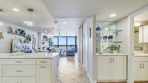 A spacious kitchen with white cabinetry, a central island, and a view to the outdoors. - Gulf Shores 203 Gorgeous 2nd Floor Beachfront View Private Balcony (Port Aransas)