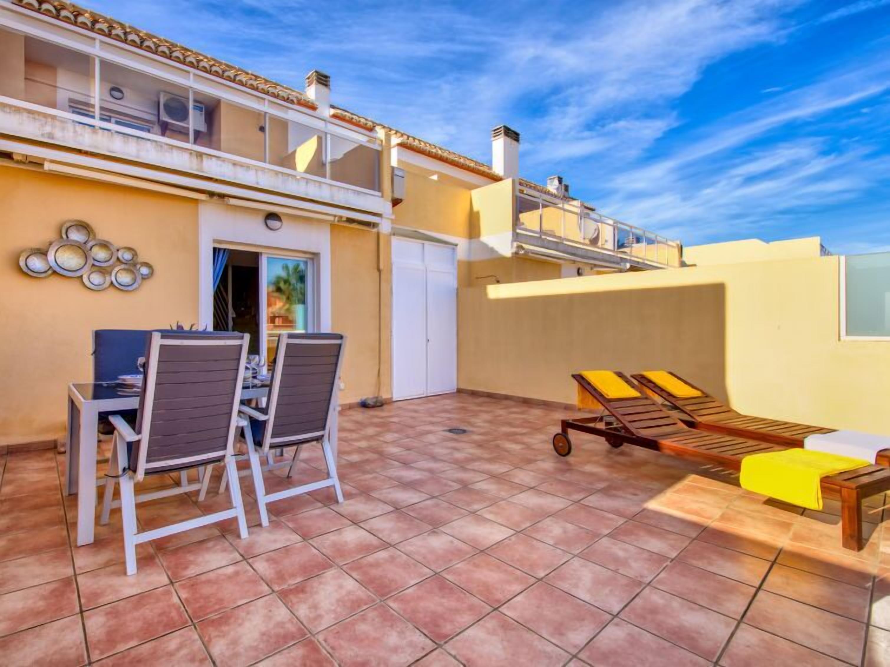 A rooftop terrace with a dining table and chairs, a sun lounger, and a small pool area.