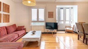 A living room with a sofa, a coffee table, a TV, and wicker chairs.