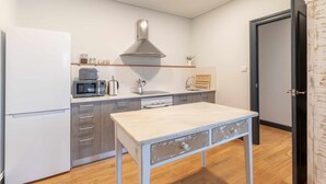 A compact kitchen with a white refrigerator, a microwave, a stove, and a sink. There's a wooden table in the center.