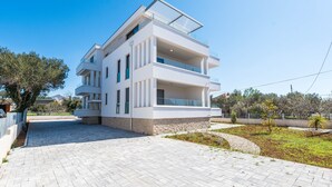 A modern two-story building with a flat roof, large windows, and a paved driveway. - Apartment Birgir in Sukošan (Sukošan)